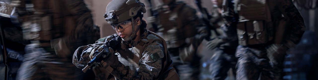 A U.S. Marine aiming a rifle leads her squad during a night mission. 