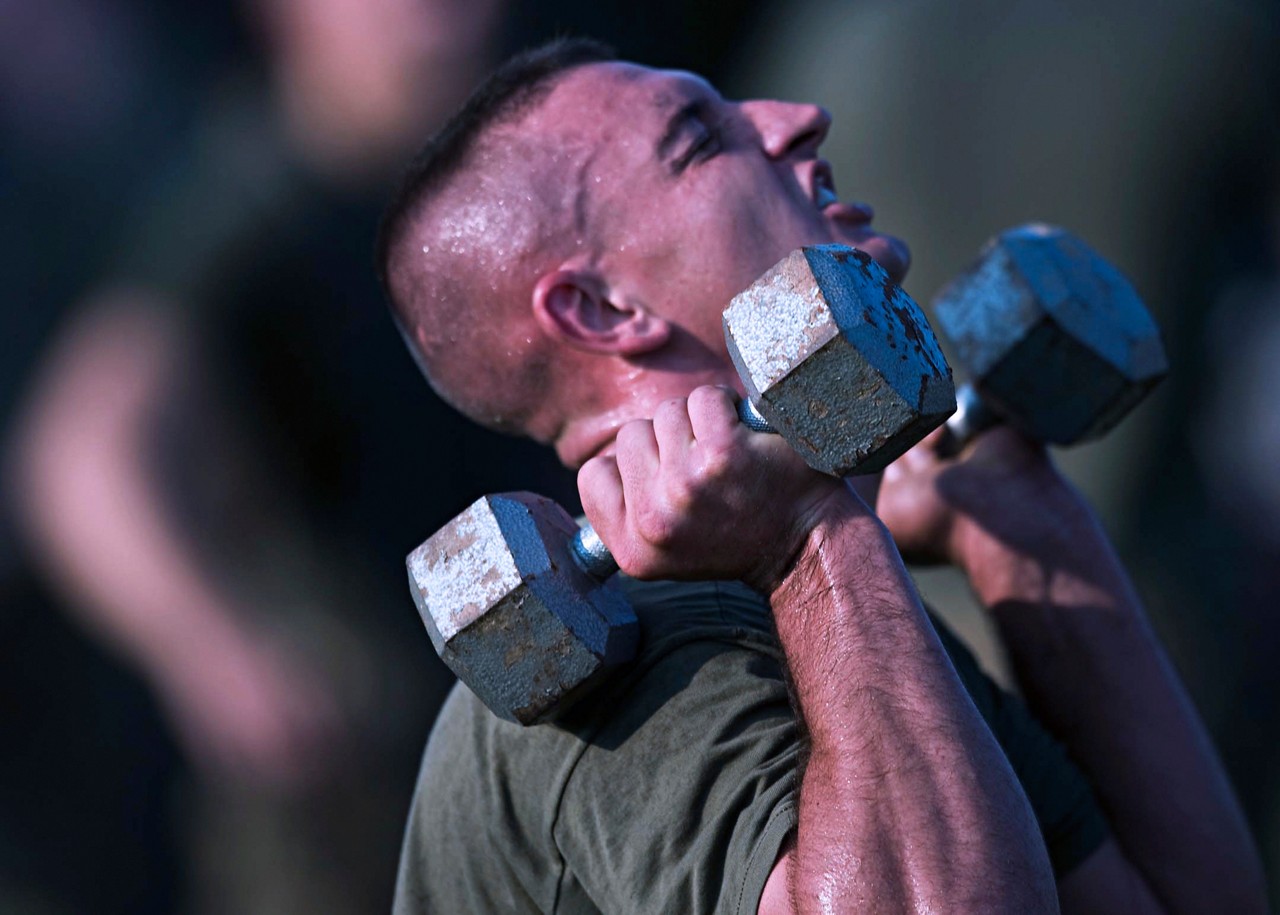 Aspiring Marine lifting dumbbells during fitness test.