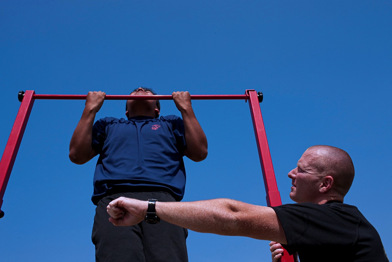 Aspring Marine doing pull ups during physical fitness test.