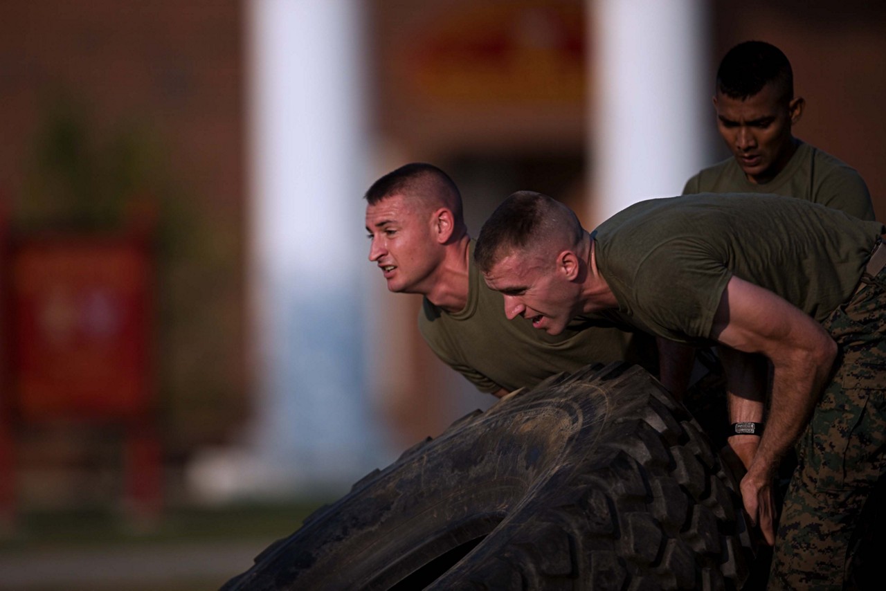 Aspiring Marines lifting tire during physical fitness test.