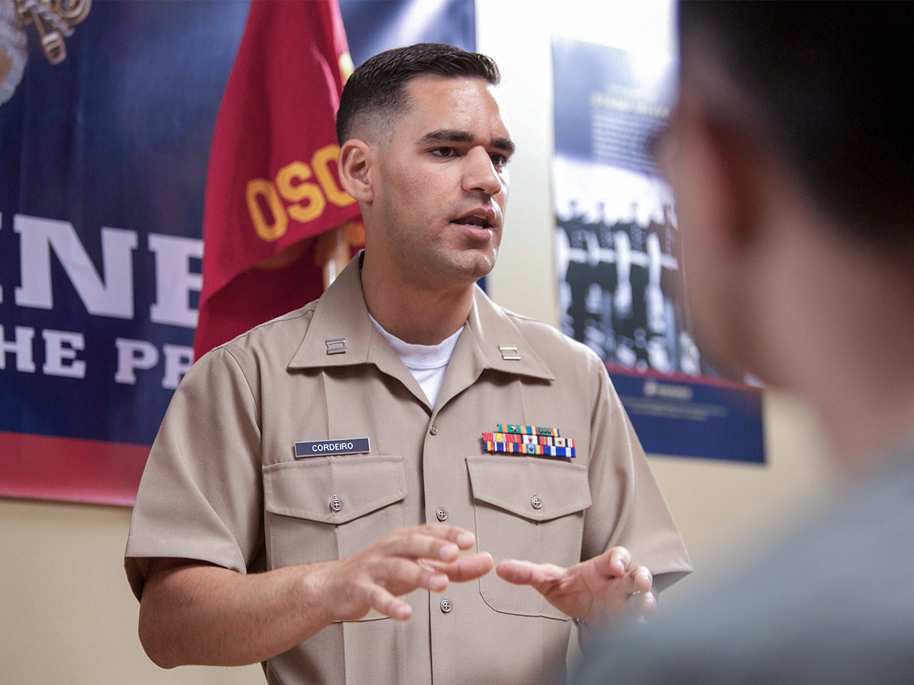 Marine officer in service uniform speaking with prospective recruit at recruiting station office.