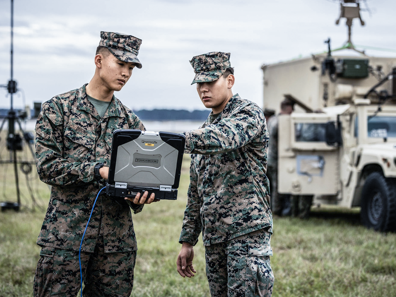 Two Marines in camouflage uniforms reviewing tactical data on rugged field computer during aviation support operations.