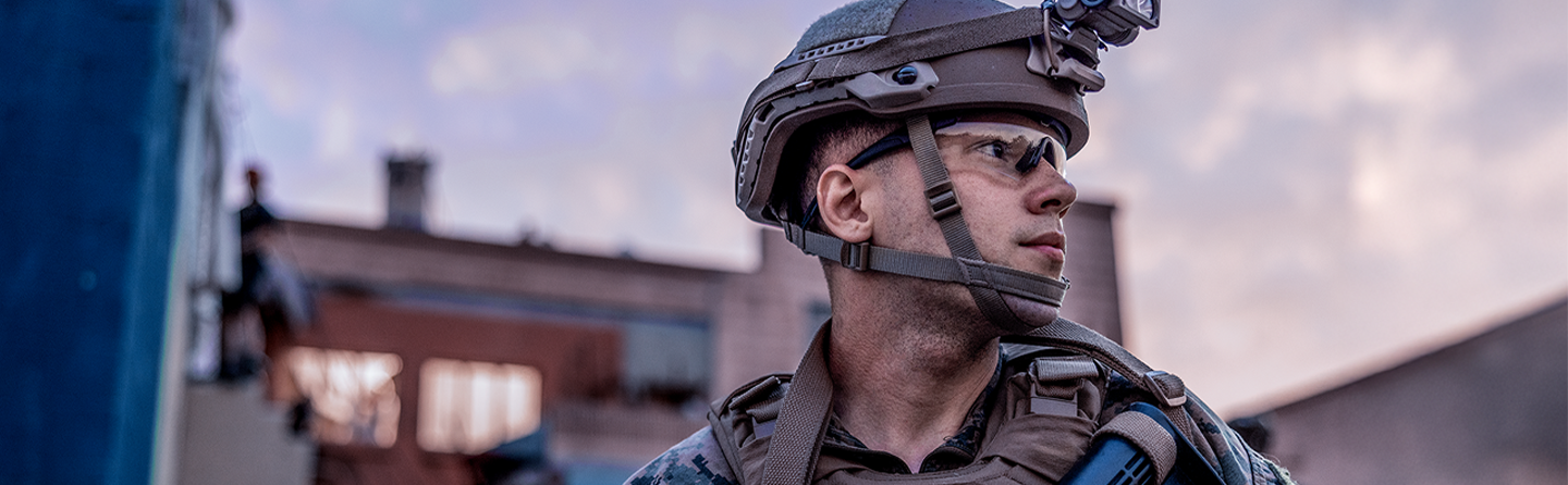 Marine wearing tactical helmet and protective eyewear in urban environment during operations.