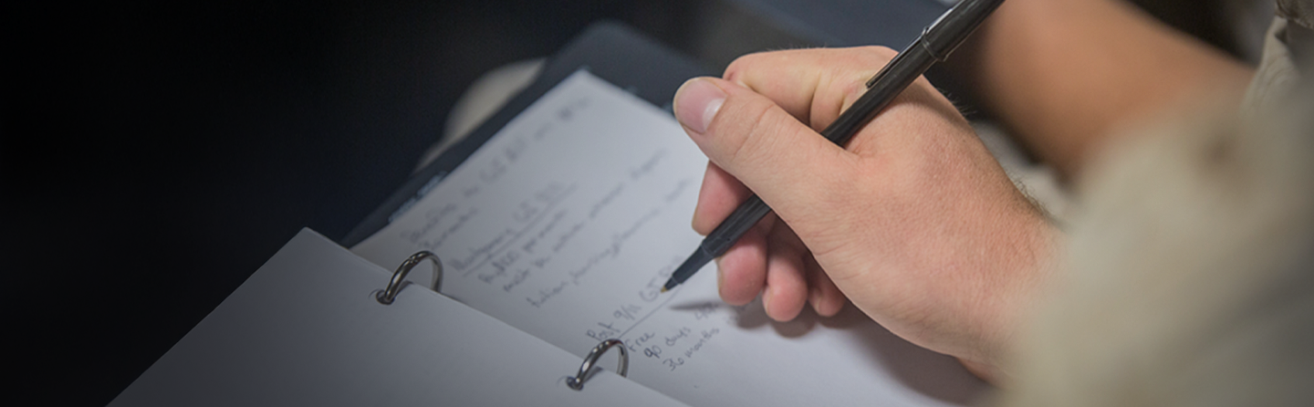 Close-up of hand from Marine holding pen writing on paper for education and learning documentation.