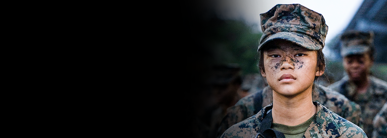 Marine in woodland uniform during field training exercise with other Marines in background.