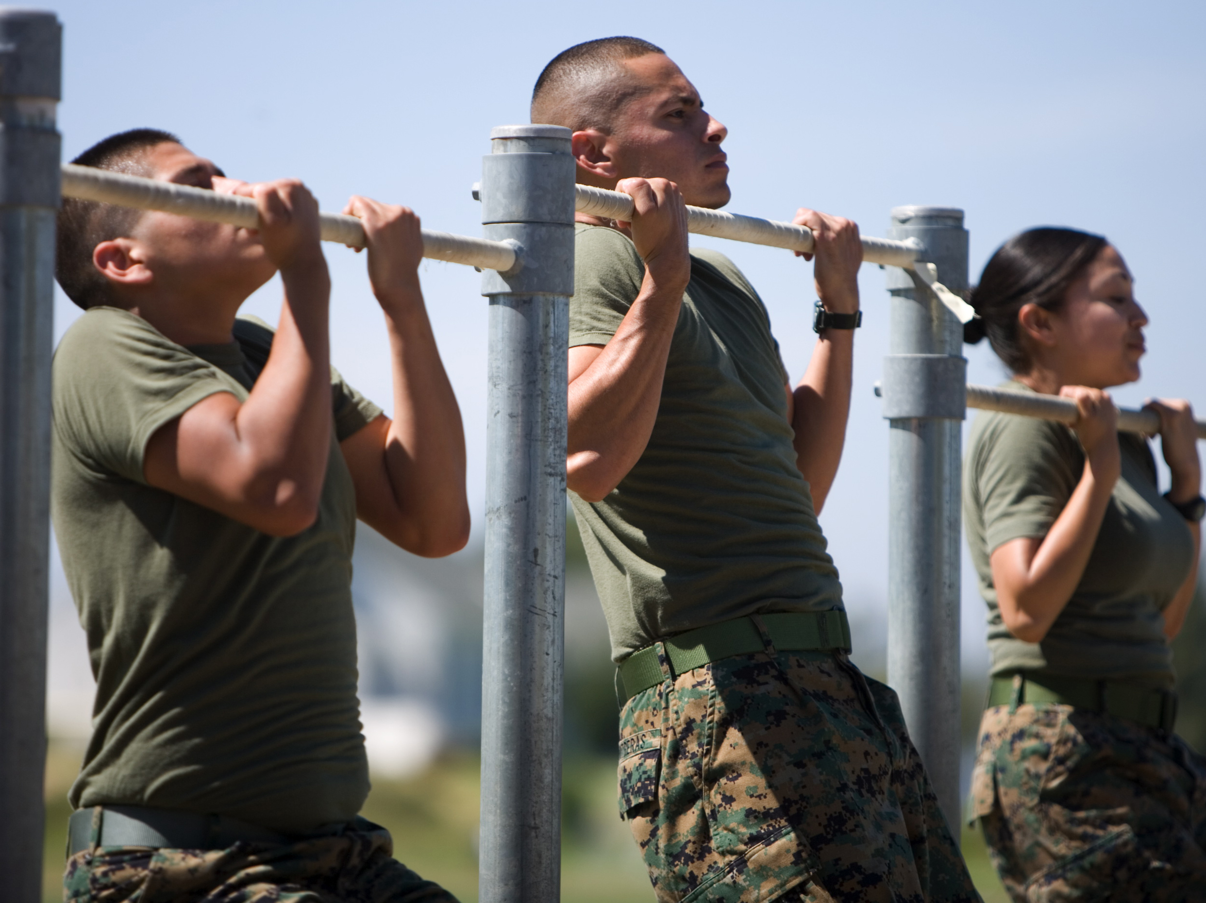  Male and female marines complete pull ups on pull up bars as part of their physical fitness assessments. 
