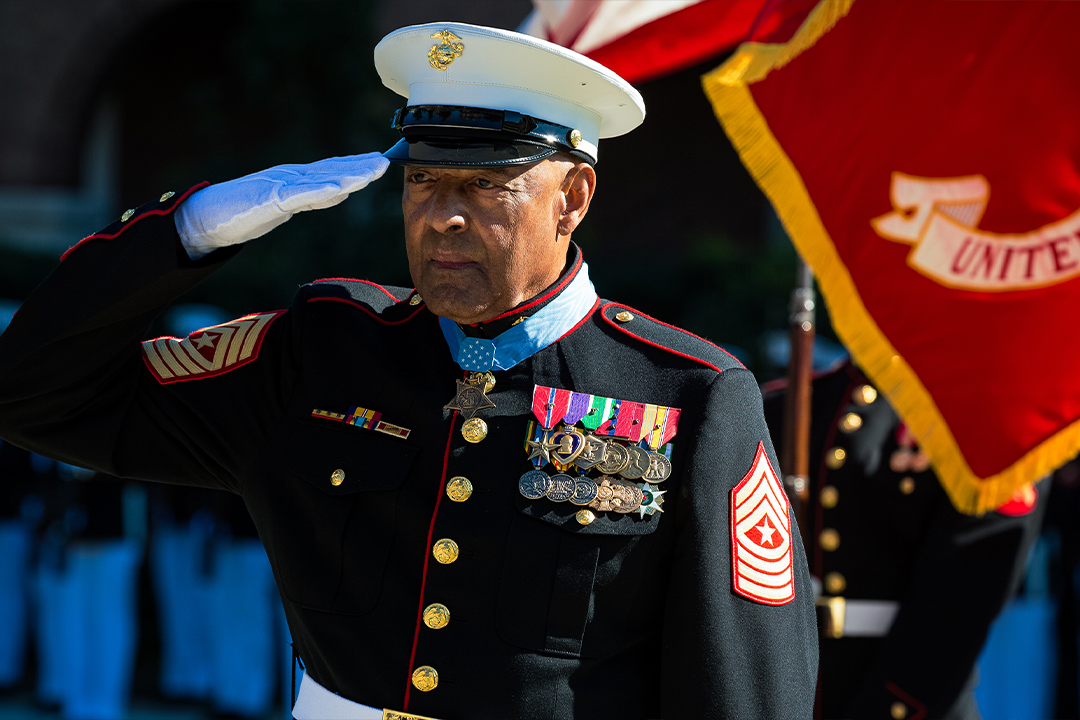 Sgt Maj Canley saluting in dress blue uniform with Medal of Honor and service ribbons at military ceremony.