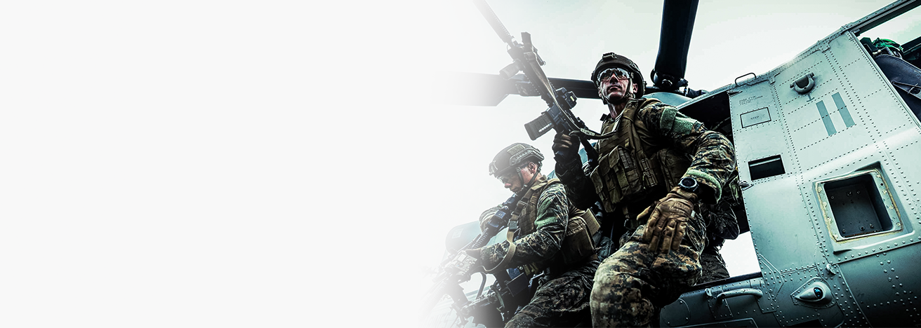 Marines in tactical gear with rifles conducting helicopter insertion training during air assault operations exercise.