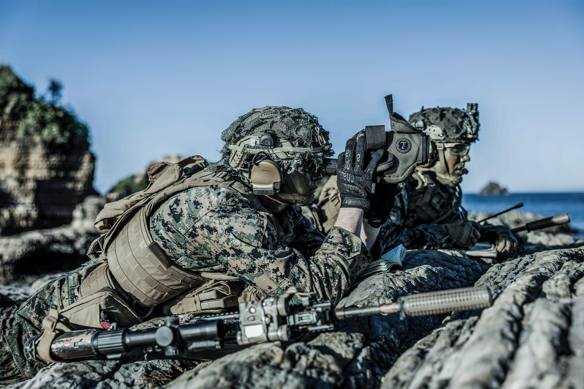 Marine Raiders conducting coastal reconnaissance with rifles and tactical gear near shoreline.