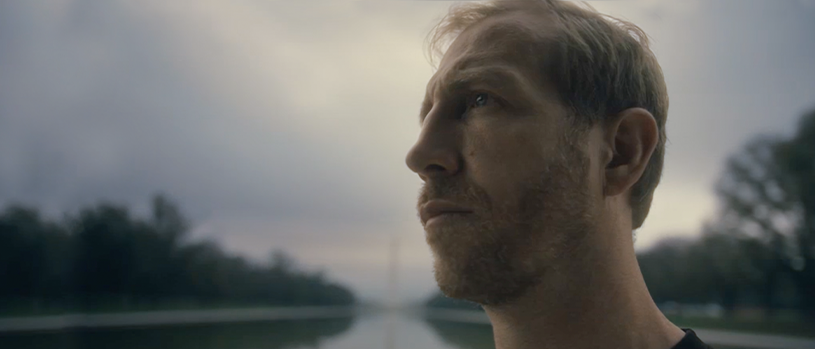 Jake Harriman, the leader of Nuru International, stands in front of a reflecting pool and the Washington Monument.