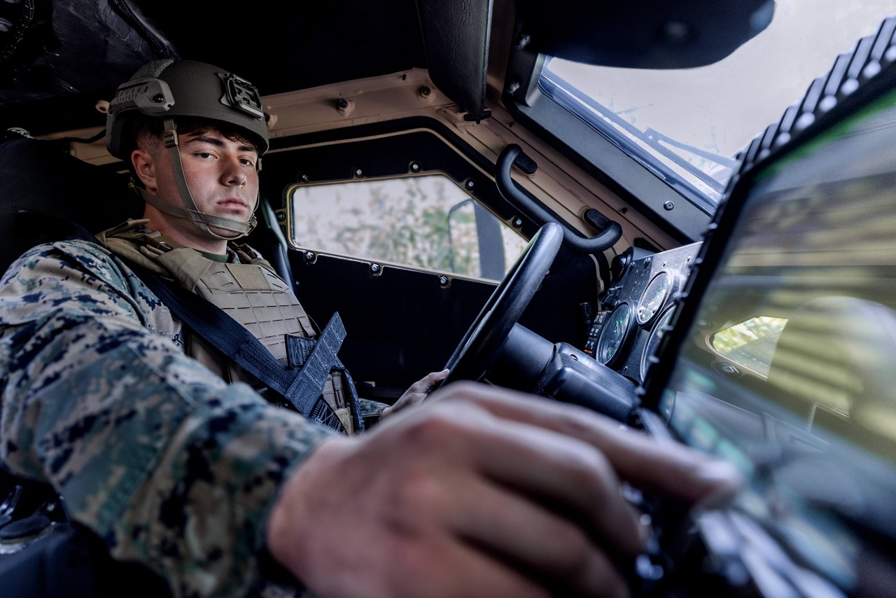 A U.S. Marine adjusts an instrument panel from the driver seat of a Joint Light Tactical Vehicle (JLTV). 